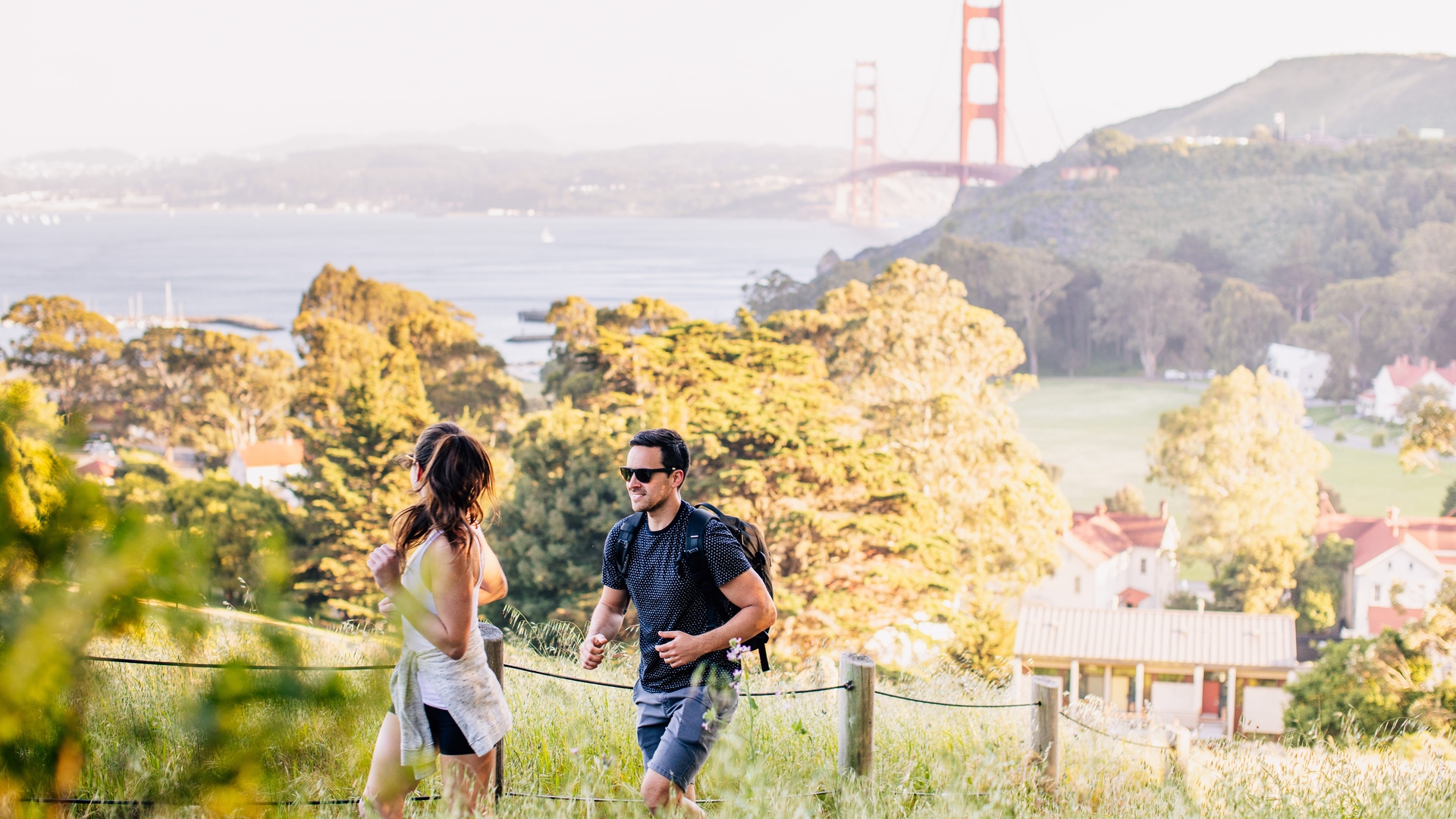 couple hiking golden gate and property in background